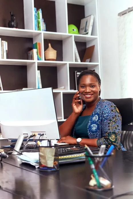 A woman sitting in front of a computer talking to the phone